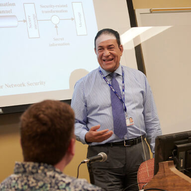 professor smiling in front of a presentation screen
