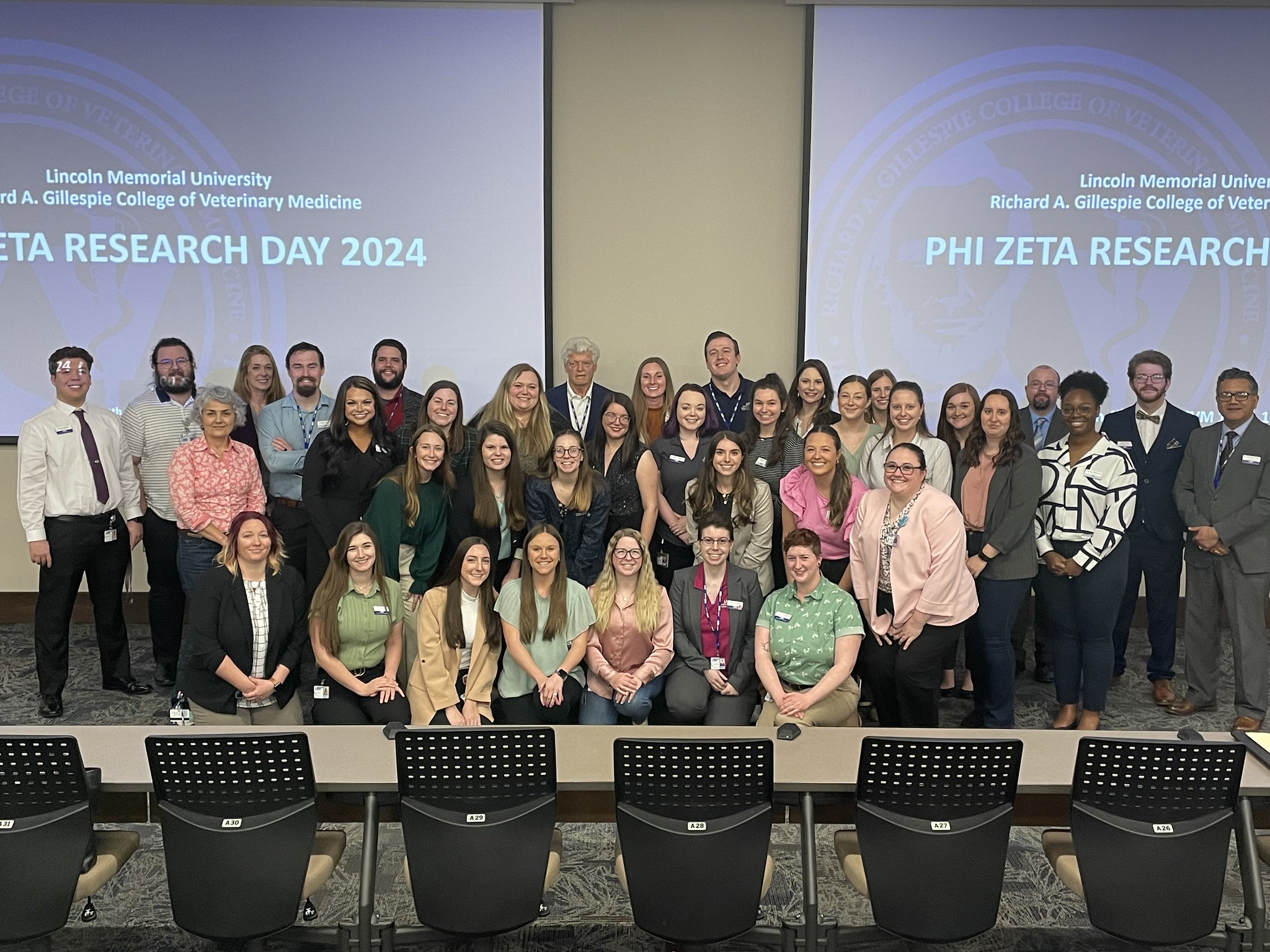 A group of students and faculty in front of a presentation that says Research Day 2024 