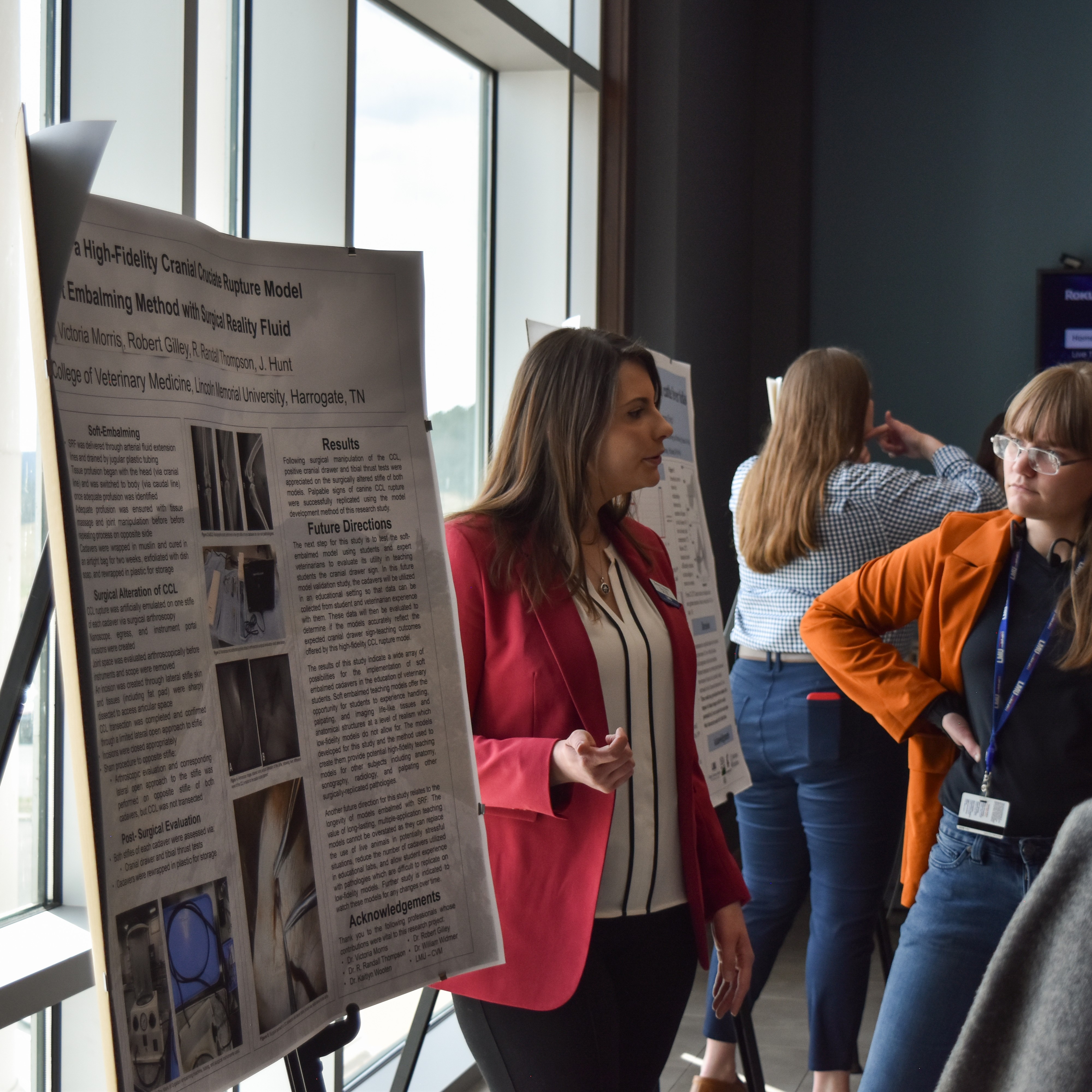 a student giving a poster presentation to 2 other students