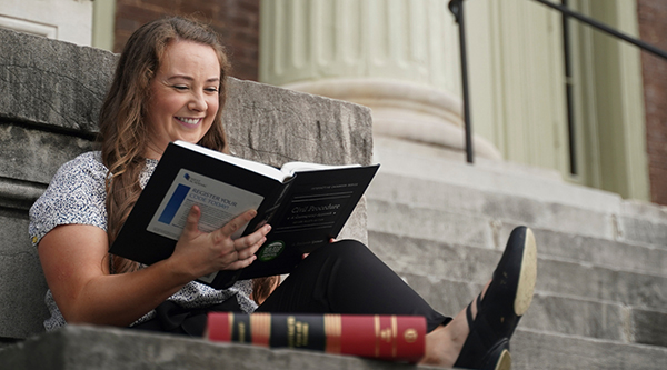 Student reading textbook on front steps