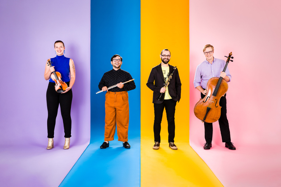 Four people standing and holding different musical instruments.