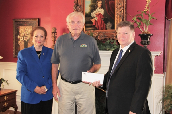 Three people posing with a donation from Mission of Hope for an endowed scholarship at LMU.