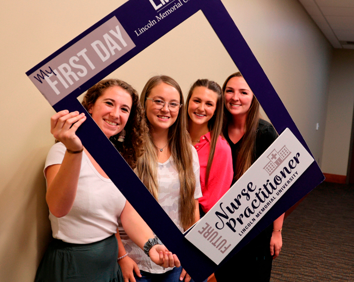 Group of four students holding a frame.