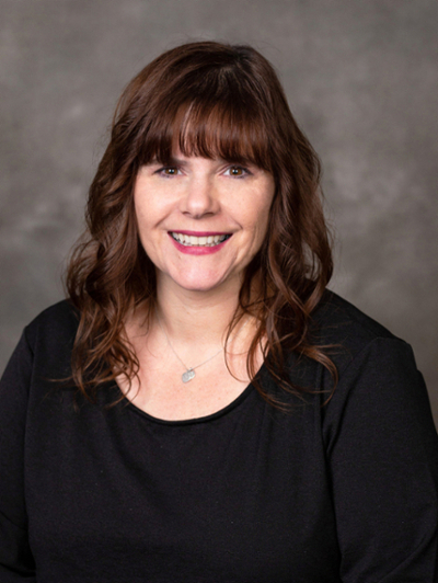 Woman smiling and pictured in a portrait with long brown hair.