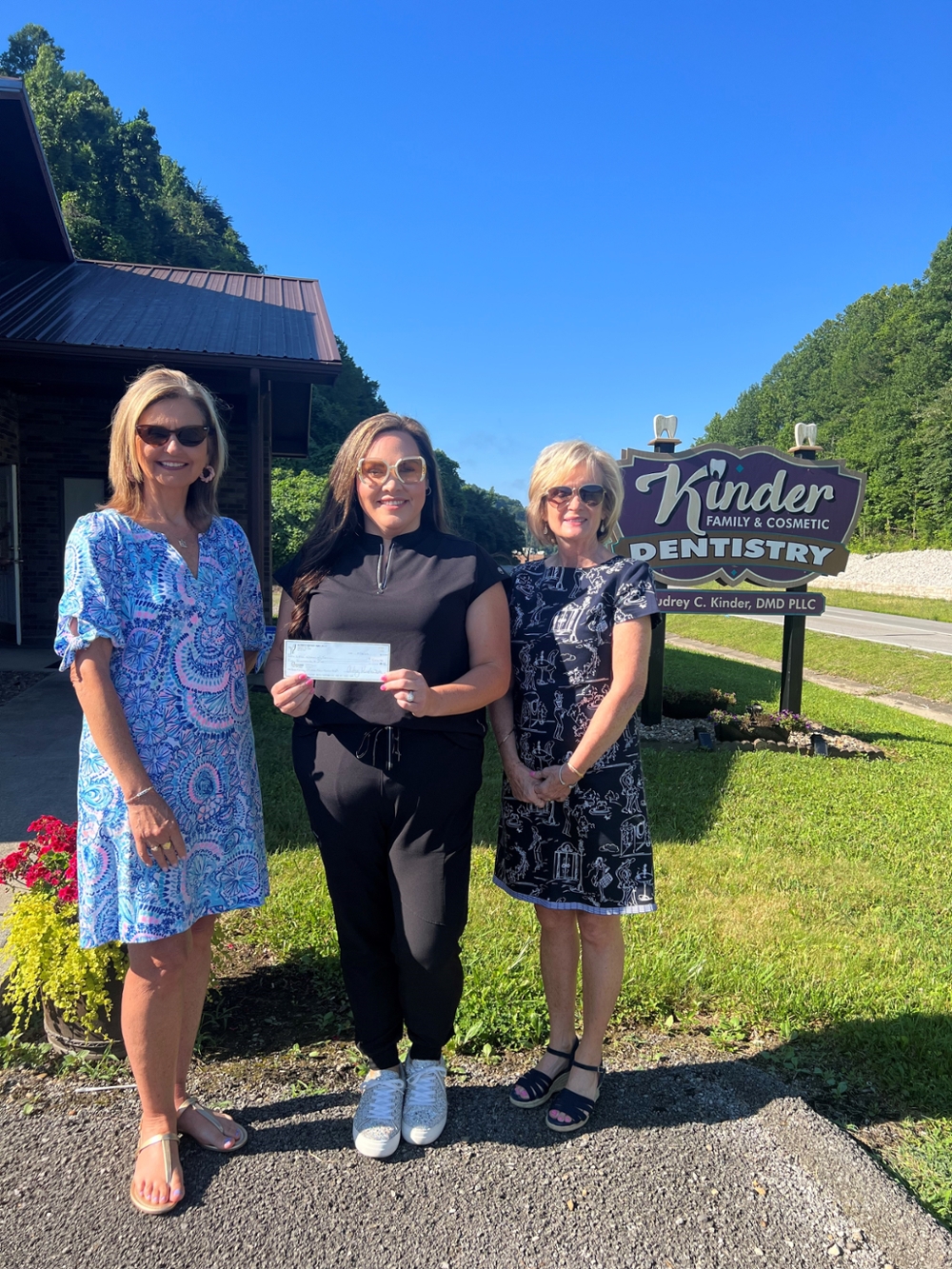 Three women standing, holding a check.