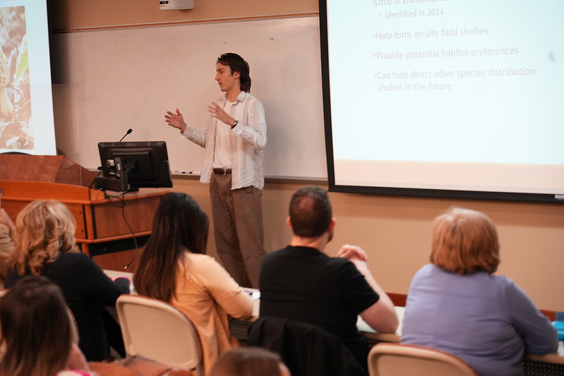 LMU undergraduate student presenting his research to a crowd.