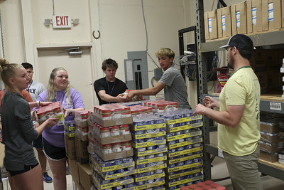 Six students working together to stock food at a food pantry.