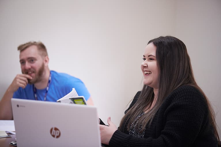 Students in front of a lap top and open textbooks