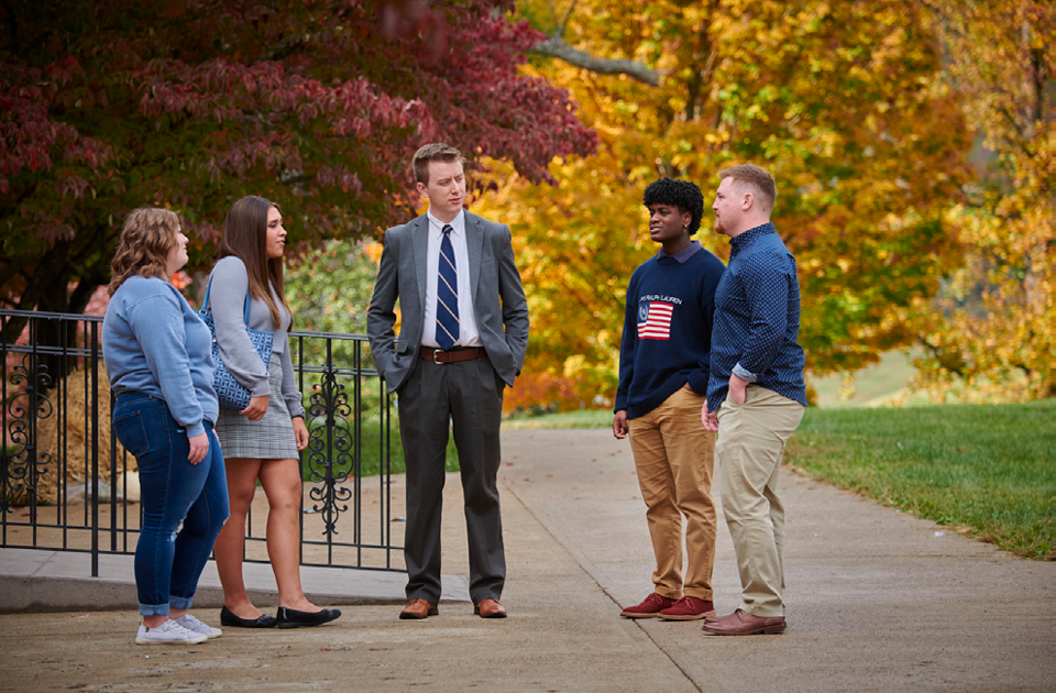 A picture of five people gathered outside talking.