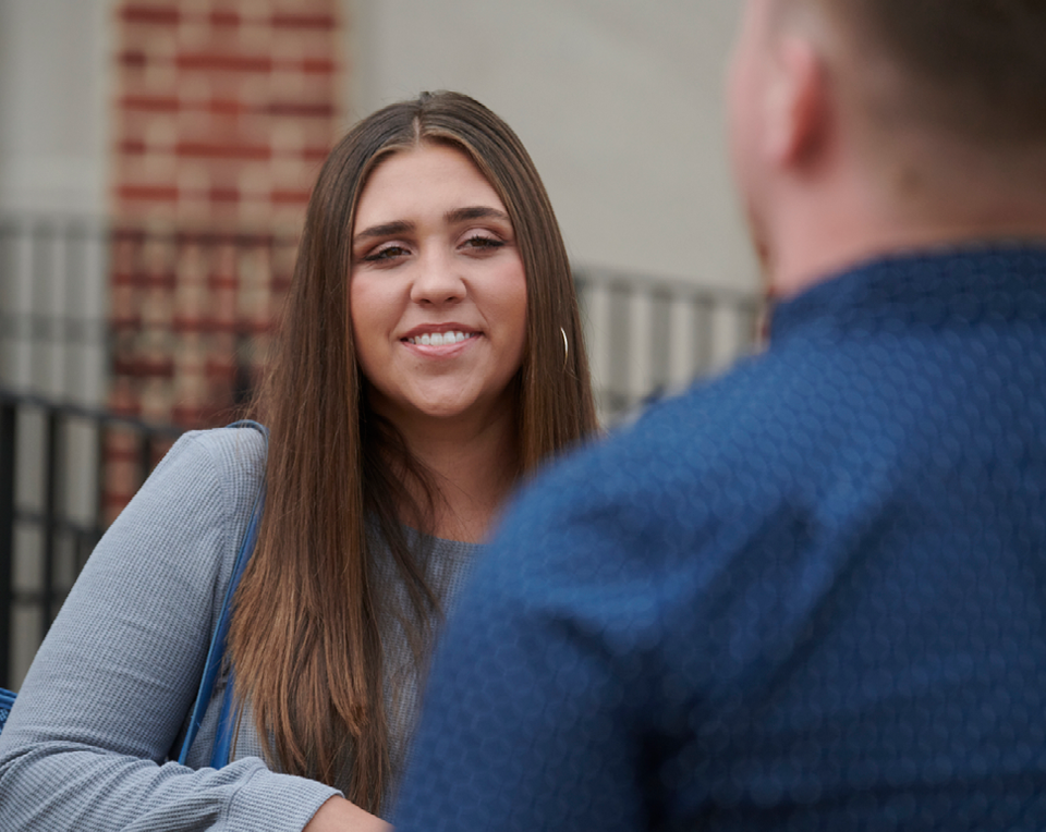 A picture of a student smiling and conversing with someone.