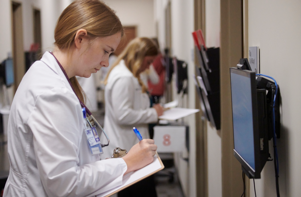 A student in a white coat taking notes.