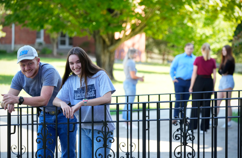 Two students leaning over a rail.