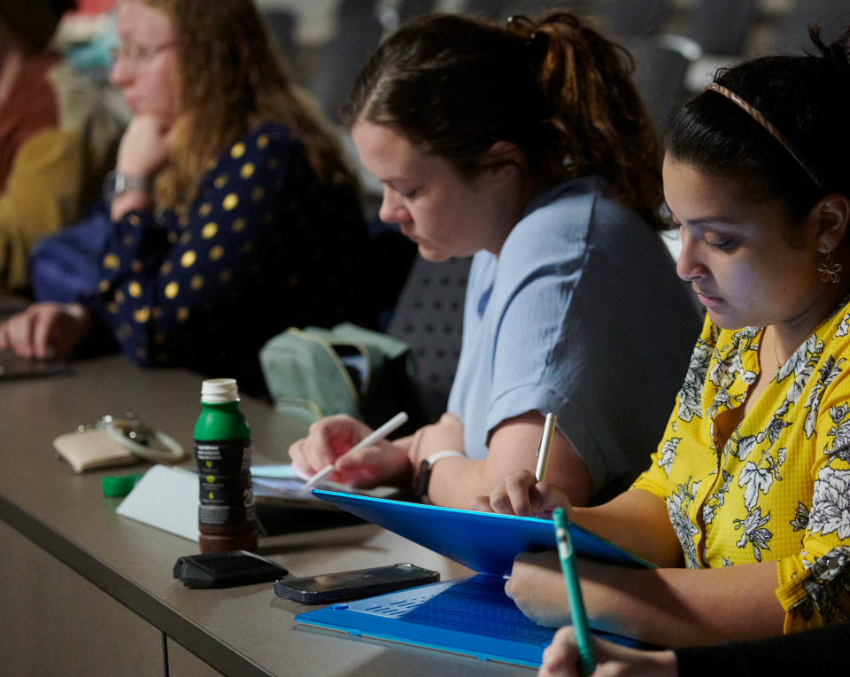 Students taking notes during a lecture.